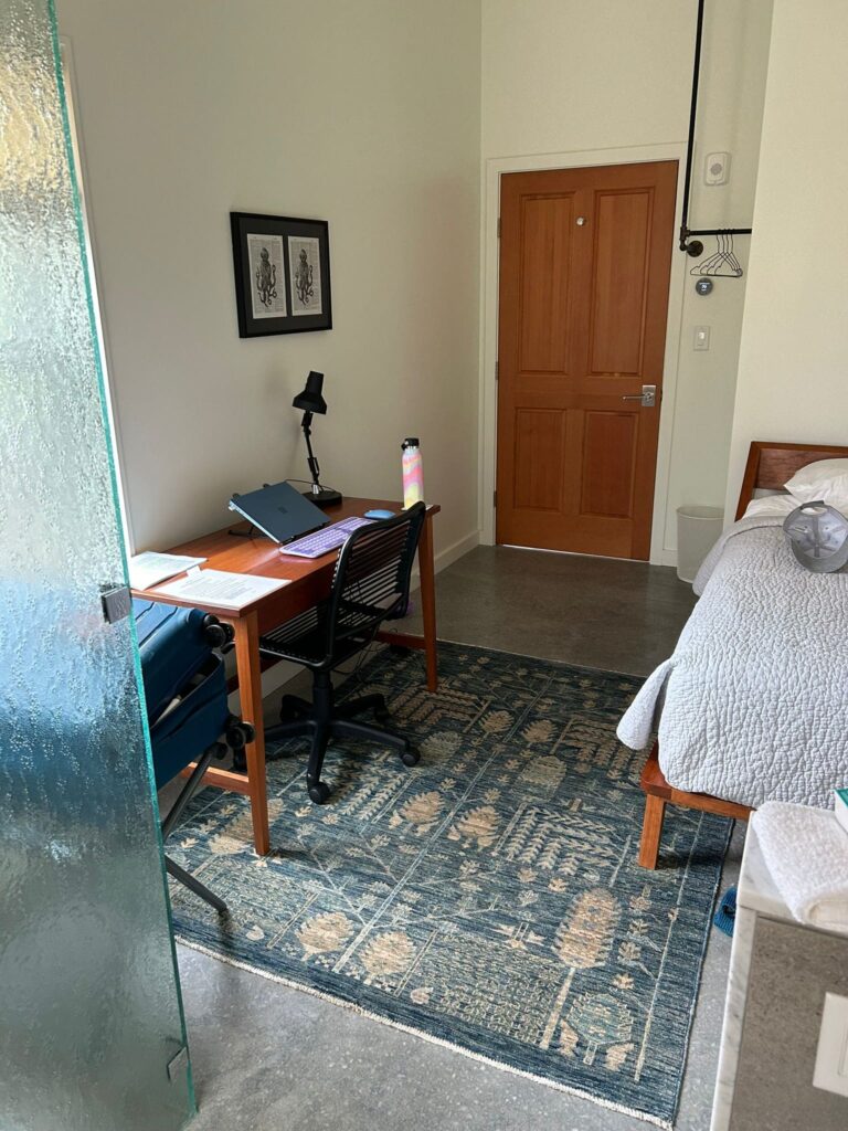 A bedroom suite at Prospect Street Writers House, including a shot of the bed, desk, and door.